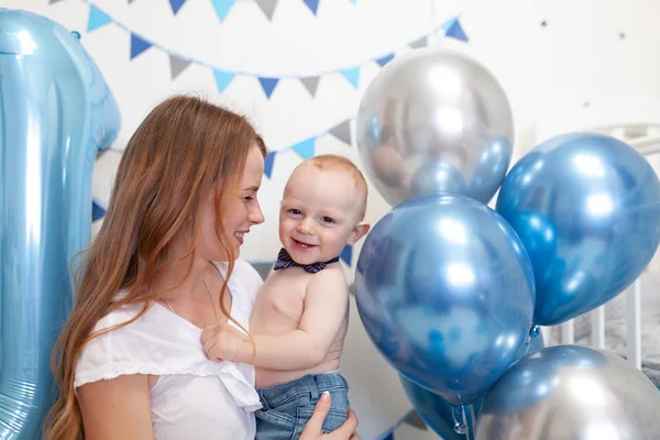 Retrato de mãe feliz e bebê no fundo de decorações de aniversário — Fotografia de Stock