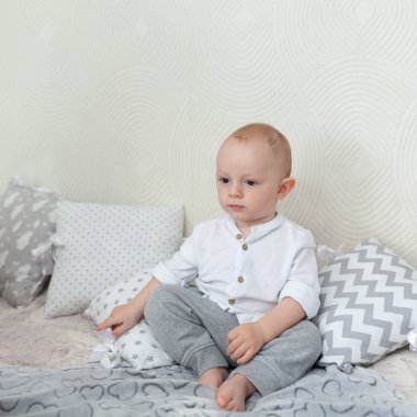 Ciddi bir çocuğun portresi. Çocuk kanepede oturur ve güler.