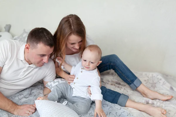 Retrato de una familia joven y feliz. Padres y bebés abrazándose y jugando en el sofá de la habitación —  Fotos de Stock