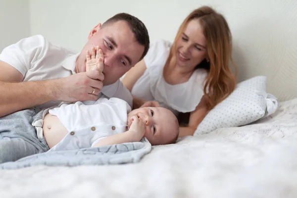 Retrato de una familia joven y feliz. Padres y bebés abrazándose y jugando en el sofá de la habitación —  Fotos de Stock