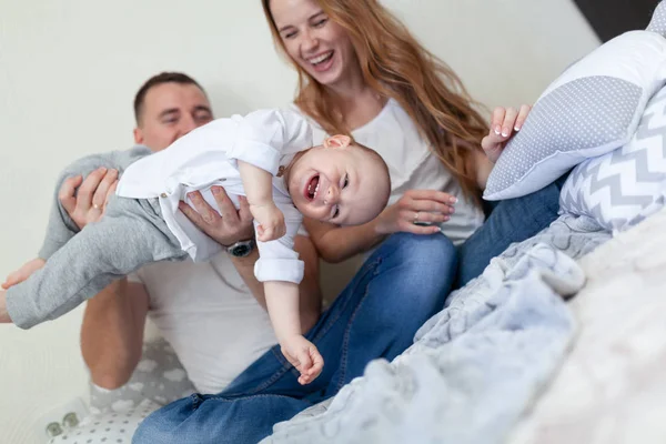 Retrato de una familia joven y feliz. Padres y bebés abrazándose y jugando en el sofá de la habitación —  Fotos de Stock