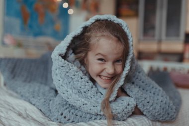 Kapalı bir odada, kanepede kitap okuyan bir kız.