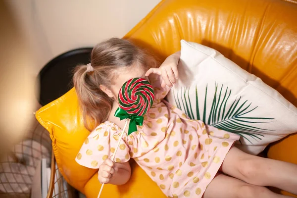 Portrait Happy Girl Candy Child Sits Yellow Sofa Laughs Indoor — Stock Photo, Image