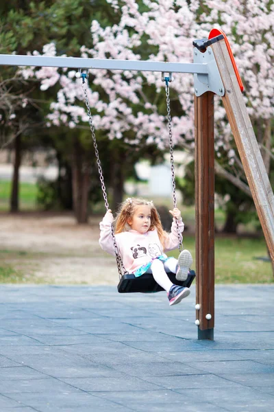 Schöne Kleine Mädchen Schaukeln Auf Einer Schaukel Auf Dem Spielplatz — Stockfoto