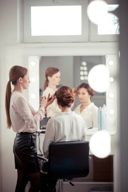 Parlak bir kuaförde kuaför işi, kız kıvırcık ve bir sürü güzel model yapıyor, kapalı bir yerde.