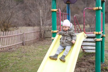 Küçük bir kız, bir çevre parkında, arka planda, açık havada, bir bahar ormanının üzerinde yürüyor.