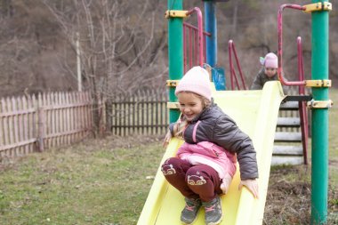 Küçük bir kız, bir çevre parkında, arka planda, açık havada, bir bahar ormanının üzerinde yürüyor.