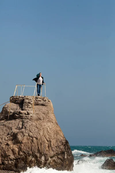 Uma Mulher Está Beira Uma Grande Rocha Olha Para Mar — Fotografia de Stock