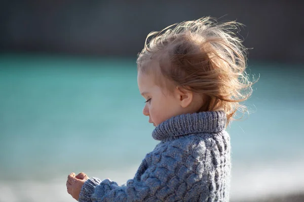 一个穿着蓝色毛衣的小孩在海面上的画像 婴儿的头发在风中飘扬 — 图库照片