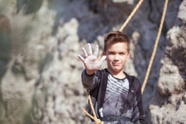 Kaya tırmanışı yapan bir genç, doğa sporları yapan bir çocuk, çocuklar için açık hava aktiviteleri yapıyor.