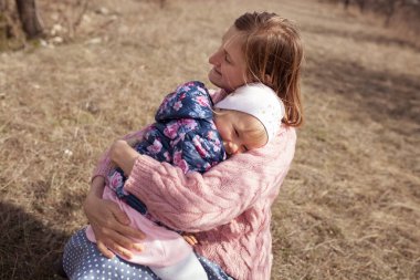 Mutlu anne ve kızın portresi çiçek açmış badem ağaçlarının arka planında, bir kadın ve bir çocuk bahar bahçesinde yürür, açık havada