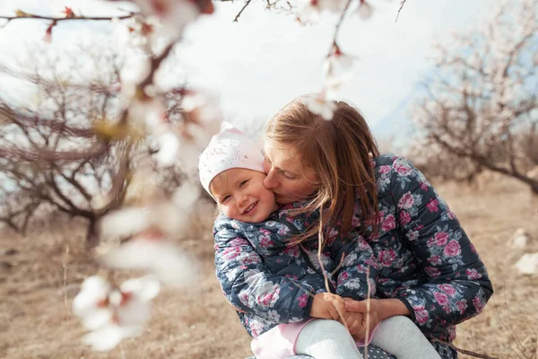 春の庭に咲くアーモンドの木を背景にした幸せな母親と娘の肖像画 女性と子供の散歩 — ストック写真