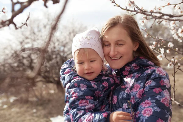 春の庭に咲くアーモンドの木を背景にした幸せな母親と娘の肖像画 女性と子供の散歩 — ストック写真