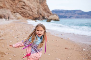 Mutlu güzel kız denizin arka planında güzel bir manzaranın arkasından deniz kıyısında yürüyor.