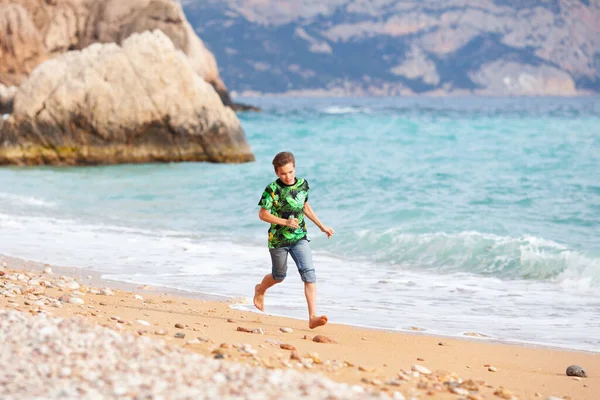 美しい風景の後ろから 海の背景に海の海岸に沿って幸せなハンサムな10代の散歩 — ストック写真