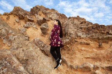 Kaya, açık hava arka planında uzun saçlı güzel bir kızın portresi, doğada aktif hamilelik.