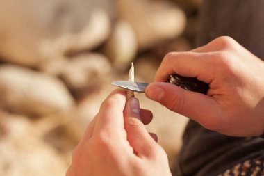 Erkeklerin elleri çakı tutar, yakın plan. Bir adam sopasını sallıyor.