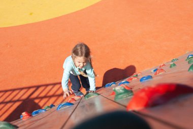 Çocuk tırmanmak için duvara tırmanıyor. Çocuklar çocuk parkında kaya tırmanışçısı