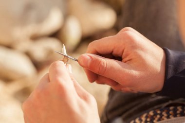 Erkeklerin elleri çakı tutar, yakın plan. Bir adam sopasını sallıyor.