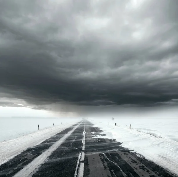 Céu tempestuoso e estrada de neve — Fotografia de Stock