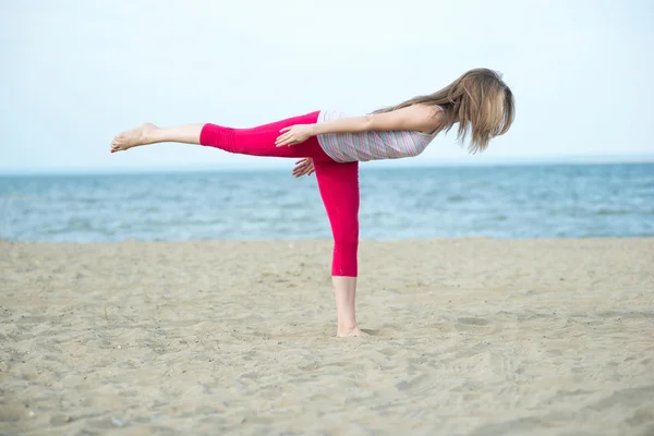 Junge Frau praktiziert Yoga. Training in der Nähe der Meeresküste. — Stockfoto