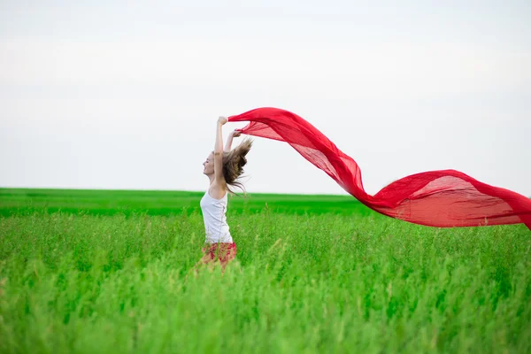 Jonge dame runing met weefsel in groene veld. Vrouw met sjaal. — Stockfoto