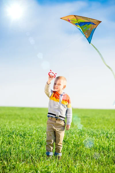 Junge spielt mit seinem Drachen auf der grünen Wiese. — Stockfoto