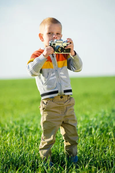 Kleiner Junge mit einer alten Kamera, die draußen schießt. — Stockfoto
