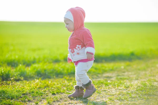 Glückliches kleines Mädchen, das auf der Wiese spaziert und in die Sonne schaut — Stockfoto