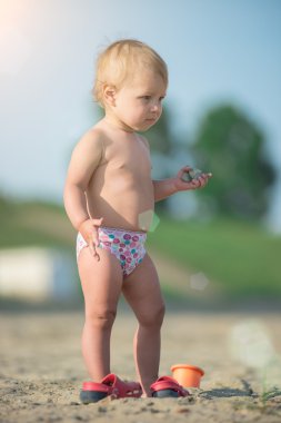 Şirin Bebek denize yakın kum plajındaki oyuncaklar ile oynama.