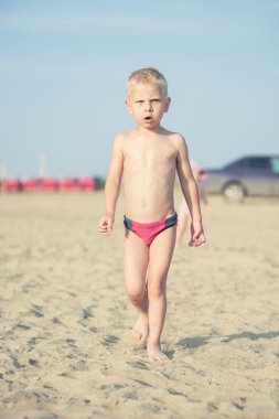 Kumsal deniz kenarında yürürken erkek sevimli bebek. Okyanus kıyısı.