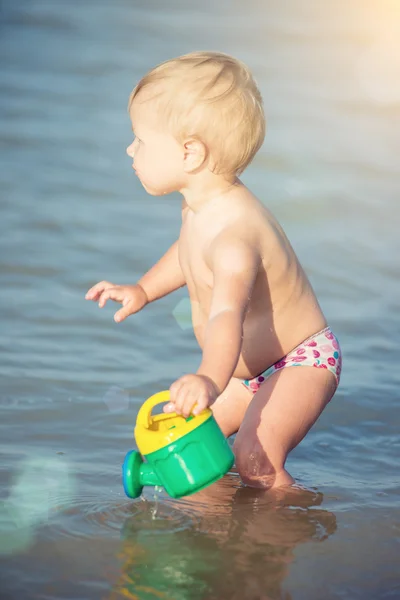 Carino bambino che gioca sulla spiaggia di sabbia e in acqua di mare . — Foto Stock