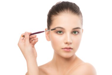 Temiz yüzü ile genç esmer kadın. Kız mükemmel cilt kozmetik fırça uygulamak. Beyaz izole.