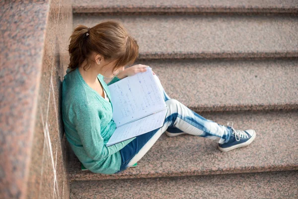 Lány ült a lépcsőn, és tudomásul olvasás — Stock Fotó