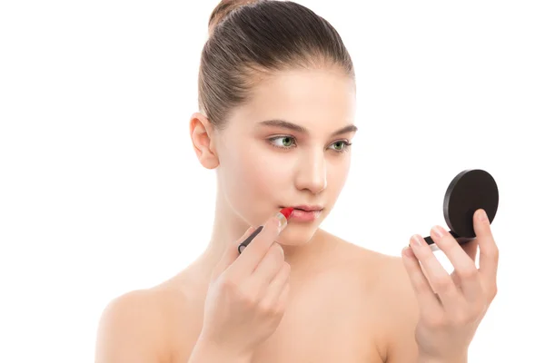 Giovane donna bruna con viso pulito perfetto applicare il rossetto usando lo specchio. Isolato su un bianco . — Foto Stock