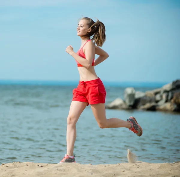 日当たりの良い夏の砂のビーチで実行している若い女性。ワークアウト。ジョギング — ストック写真