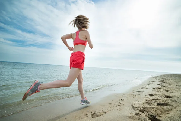 Jovem correndo na ensolarada praia de areia de verão. Treino. Correr. Fotografia De Stock