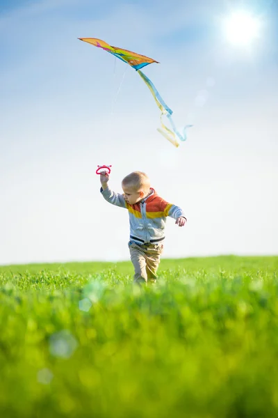 Молодий хлопчик грає зі своїм змієм у зеленому полі . — стокове фото
