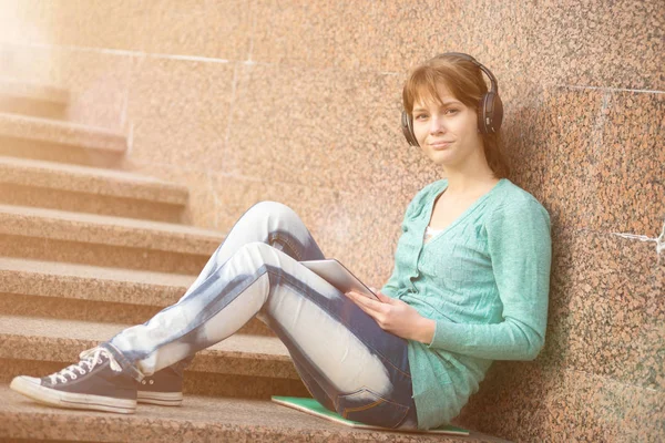 Linda jovem estudante com bloco de notas e fones de ouvido. Estudante exterior . — Fotografia de Stock