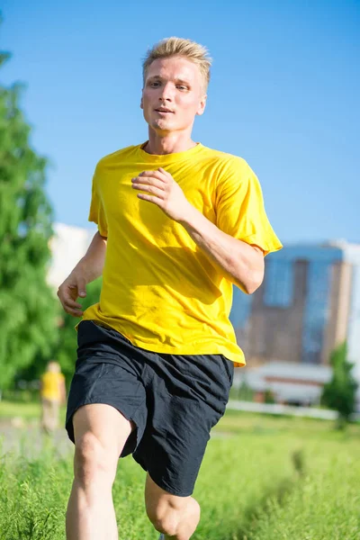 Sporty man jogging in city street park. Outdoor fitness. — Stock Photo, Image