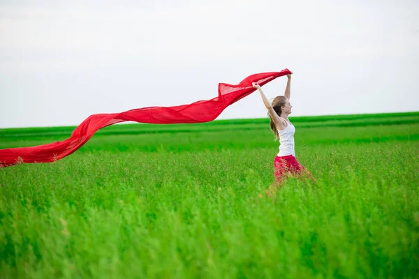 Jeune femme courant avec des tissus dans un champ vert. Femme avec écharpe . — Photo