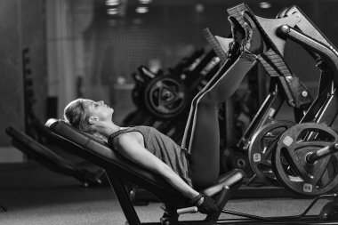 Bacaklar için ağırlıklar basın makine kullanan sportif kadın. Spor salonu.