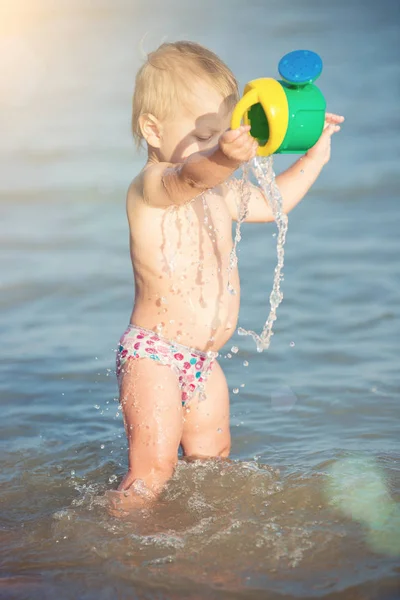 Słodkie dziecko grając na piaszczystej plaży i w wodzie morskiej. — Zdjęcie stockowe