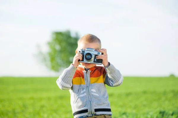 Menino com uma câmera velha atirando ao ar livre . — Fotografia de Stock