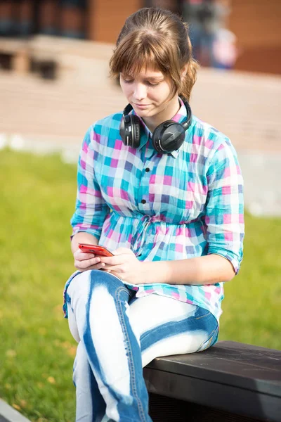 携帯電話で若い大学生少女の笑みを浮かべてテキスト メッセージ。キャンパス — ストック写真