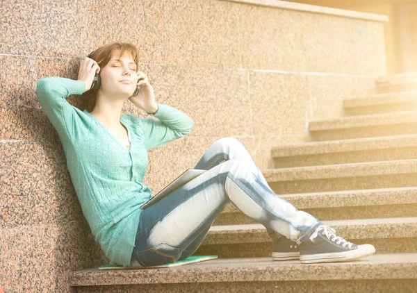 Mooie jonge vrouw student met een koptelefoon. Buiten muziek meisje — Stockfoto