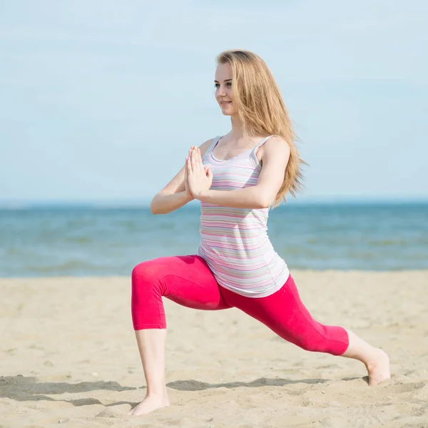 Young lady practicing yoga. Workout near ocean sea coast. — Stock Photo, Image