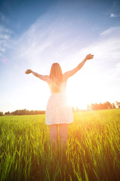 Felicidade mulher ficar ao ar livre sob a luz do sol do pôr do sol — Fotografia de Stock