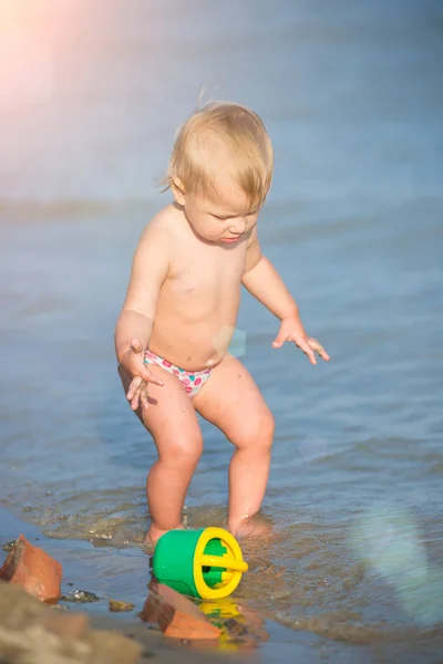 Carino bambino che gioca sulla spiaggia di sabbia e in acqua di mare . — Foto Stock