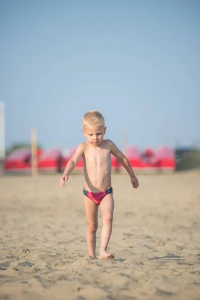 Милый мальчик, гуляющий по песчаному пляжу у моря. Берег океана . — стоковое фото